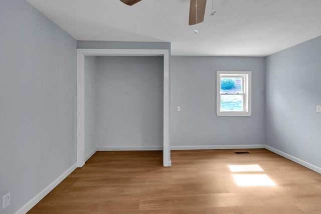 unfurnished bedroom with baseboards, ceiling fan, wood finished floors, and visible vents