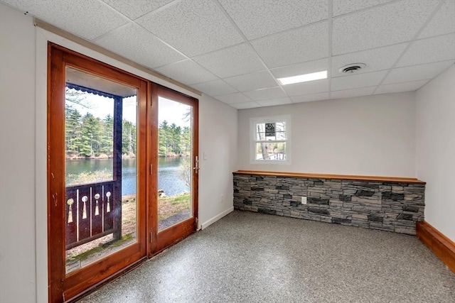 empty room with a water view, baseboards, visible vents, and a drop ceiling