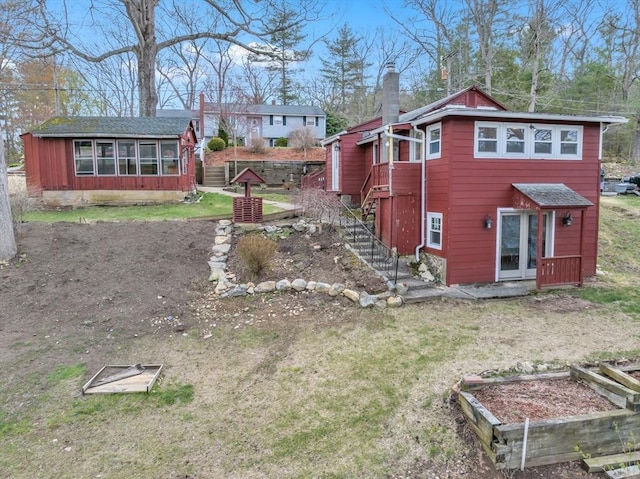 view of side of property featuring stairs, a garden, and a chimney