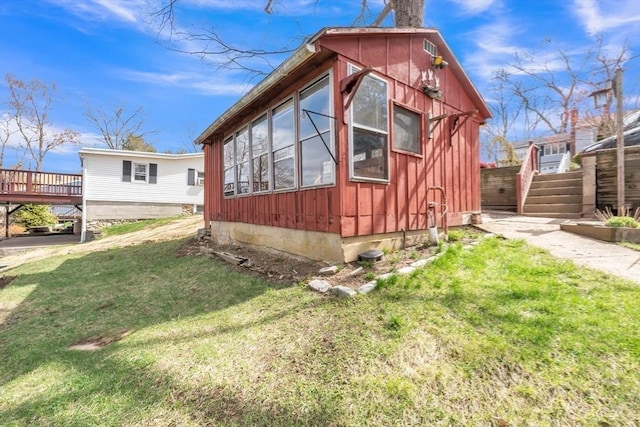 view of side of property featuring a yard, board and batten siding, and a wooden deck