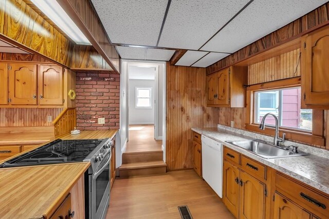 kitchen with white dishwasher, a sink, stainless steel range with electric stovetop, wood counters, and visible vents