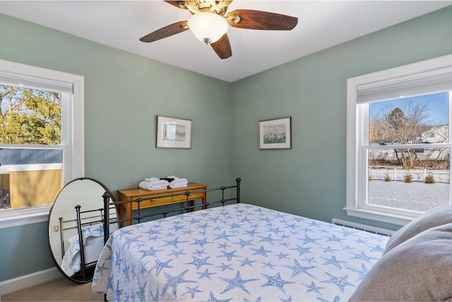 carpeted bedroom featuring ceiling fan, a baseboard radiator, and multiple windows