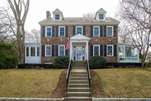 colonial house with a sunroom and a front lawn