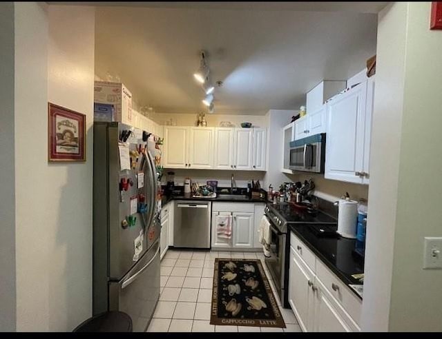 4 Charlesgate E Unit 604, Boston, MA 02215 - kitchen featuring appliances with stainless steel finishes, light tile patterned floors, dark countertops, white cabinetry, and a sink