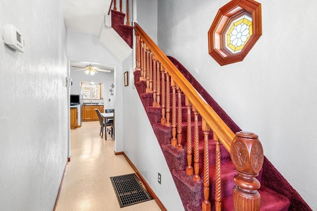 stairway with baseboards, visible vents, and a ceiling fan