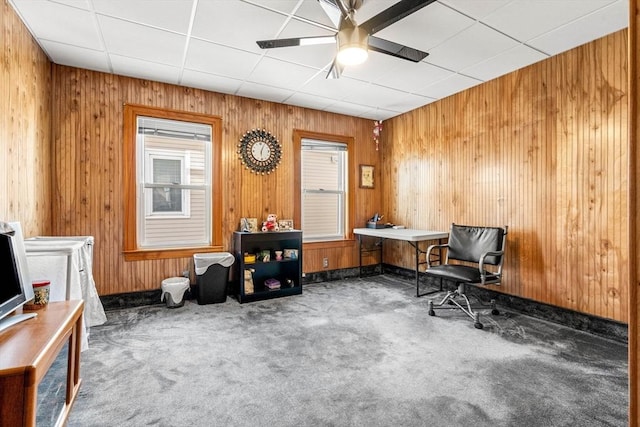 misc room featuring carpet floors, wood walls, and ceiling fan