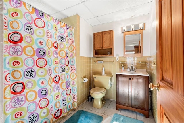 bathroom with tile walls, a shower with shower curtain, toilet, a drop ceiling, and tile patterned floors