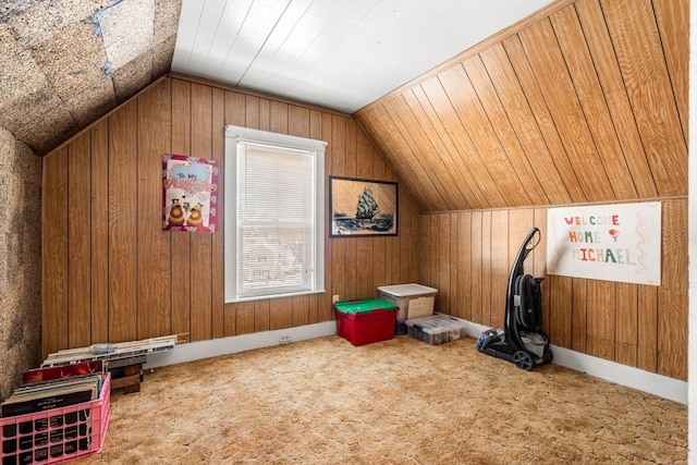 bonus room with vaulted ceiling, wood walls, and carpet flooring