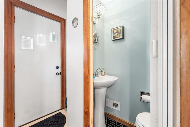 half bathroom with baseboards, visible vents, and toilet