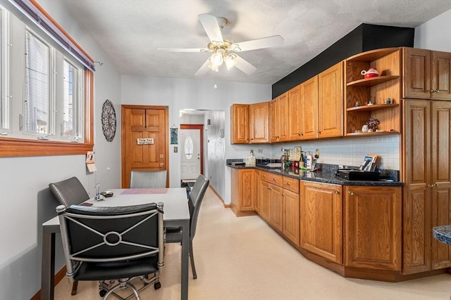 kitchen with open shelves, a ceiling fan, brown cabinetry, and backsplash