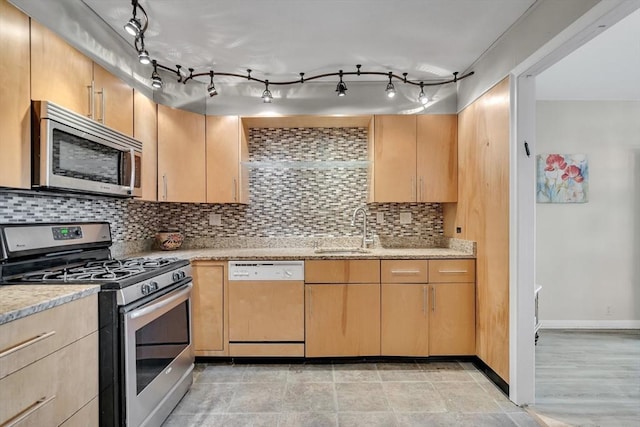 kitchen featuring light brown cabinetry, sink, stainless steel appliances, light stone countertops, and decorative backsplash