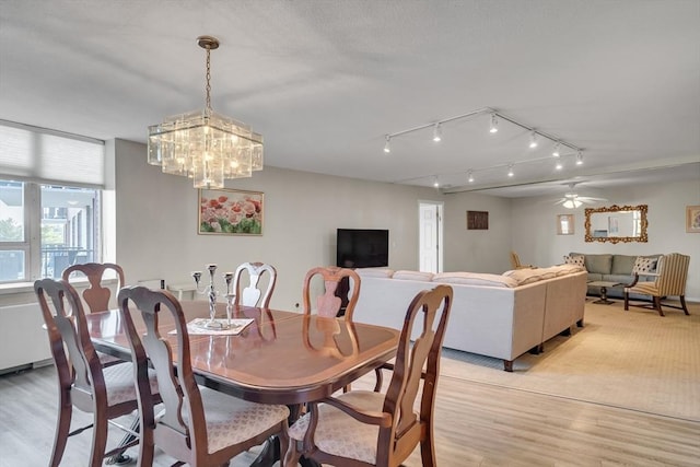 dining space featuring ceiling fan with notable chandelier and light hardwood / wood-style flooring