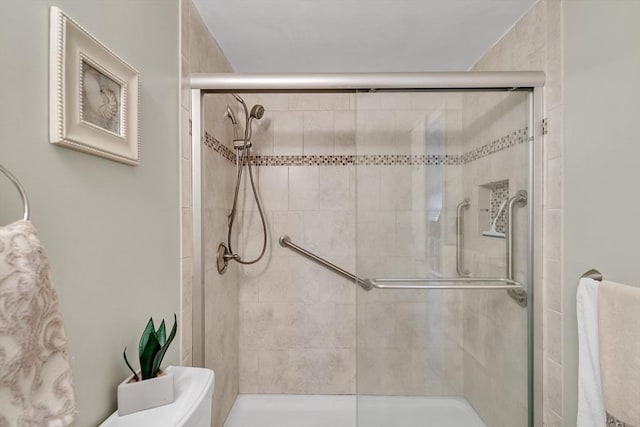 bathroom featuring a shower with door and toilet