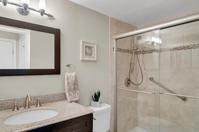 bathroom with vanity, a shower with shower door, and toilet