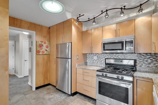 kitchen with light stone counters, backsplash, and appliances with stainless steel finishes