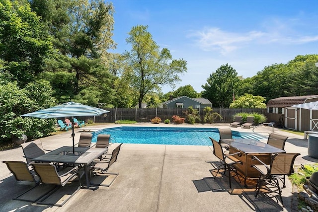 1 Redgate Ln, Holden, MA 01520 - view of swimming pool featuring a storage unit, a patio area, a fenced backyard, outdoor dining space, and view of scattered trees