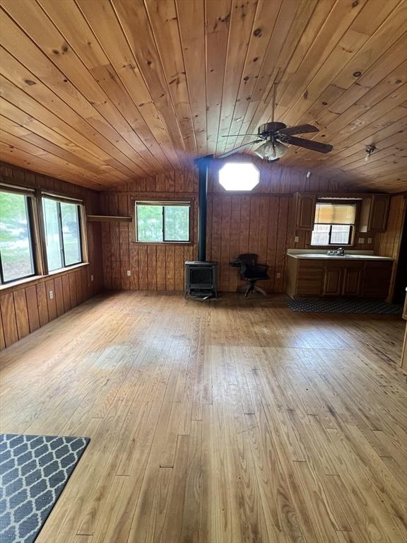 11 Summit Ave, Lakeville, MA 02347 - unfurnished living room with a wood stove, wooden ceiling, wood-type flooring, ceiling fan, and wooden walls