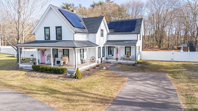 view of front of house featuring solar panels, covered porch, and a front lawn