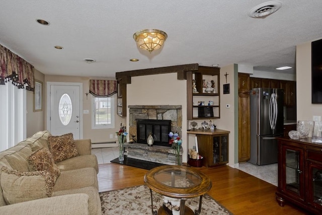 90 Westwood Ave, East Longmeadow, MA 01028 - living area featuring a baseboard heating unit, a stone fireplace, visible vents, and light wood-type flooring