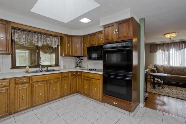90 Westwood Ave, East Longmeadow, MA 01028 - kitchen featuring brown cabinets, a sink, light countertops, light tile patterned floors, and black appliances