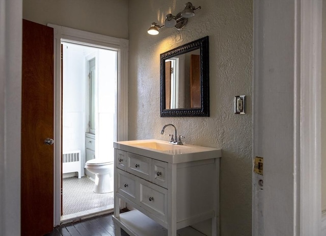 bathroom with toilet, hardwood / wood-style flooring, radiator, and vanity