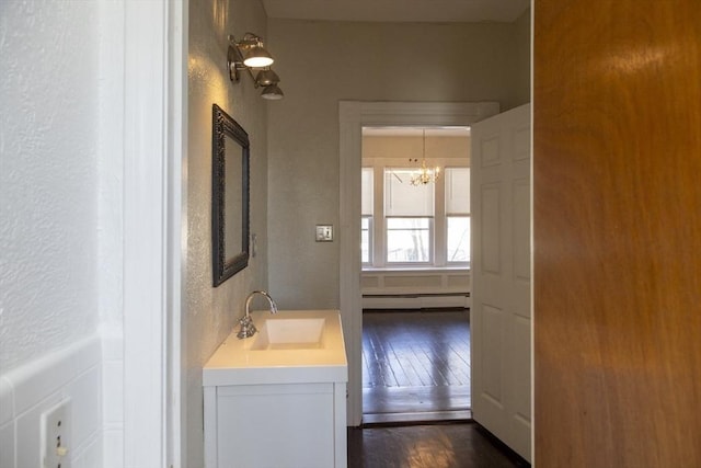 bathroom featuring wood-type flooring, vanity, a chandelier, and a baseboard radiator