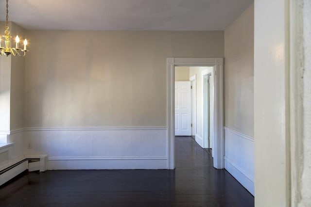 empty room featuring a chandelier, dark hardwood / wood-style flooring, and a baseboard heating unit