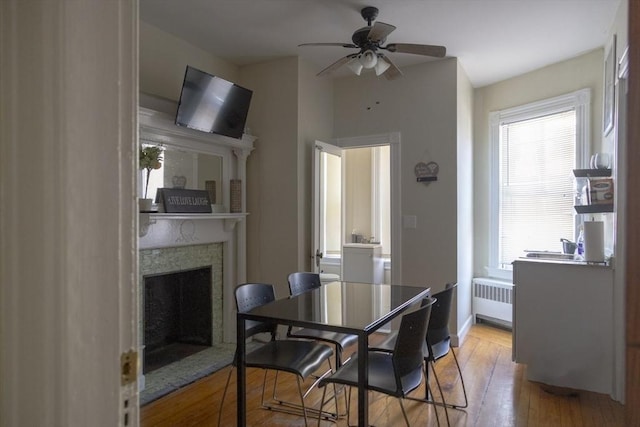 dining room with light wood-type flooring, radiator heating unit, and ceiling fan