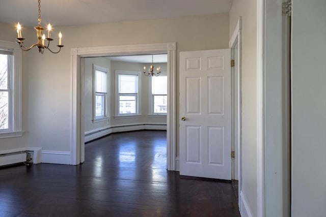 unfurnished dining area with a wealth of natural light, dark hardwood / wood-style flooring, and a notable chandelier