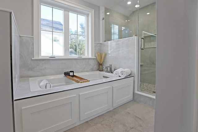 bathroom featuring plenty of natural light and separate shower and tub