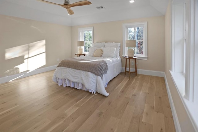 bedroom with light wood-type flooring, a raised ceiling, and ceiling fan