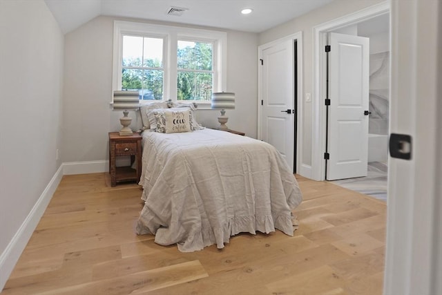 bedroom with vaulted ceiling and light hardwood / wood-style flooring