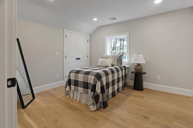 bedroom with light wood-type flooring and lofted ceiling