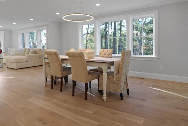 dining area with a healthy amount of sunlight, light wood-type flooring, and crown molding