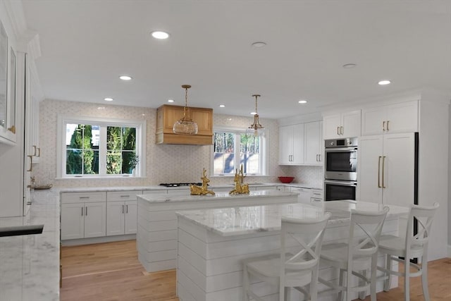 kitchen with white cabinetry, stainless steel double oven, decorative light fixtures, and built in fridge