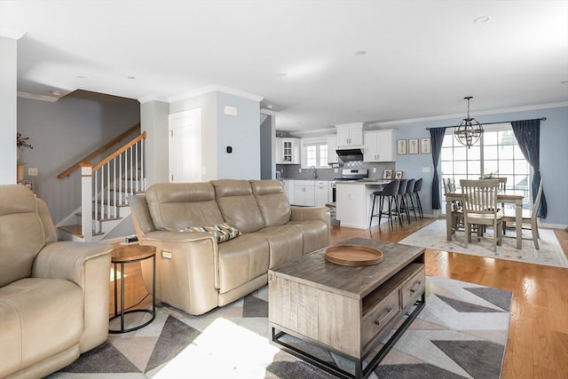 27 Mill St Unit B, Quincy, MA 02169 - living room featuring crown molding, a chandelier, light wood-style floors, stairs, and baseboards