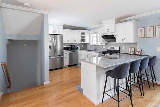 27 Mill St Unit B, Quincy, MA 02169 - kitchen with appliances with stainless steel finishes, a peninsula, a sink, white cabinetry, and extractor fan