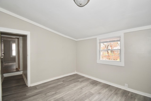 spare room with wood-type flooring, crown molding, and lofted ceiling