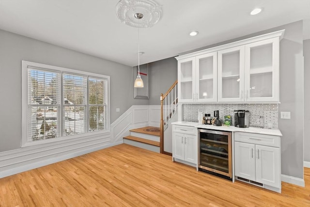 bar featuring wine cooler, pendant lighting, stairway, decorative backsplash, and light wood-type flooring