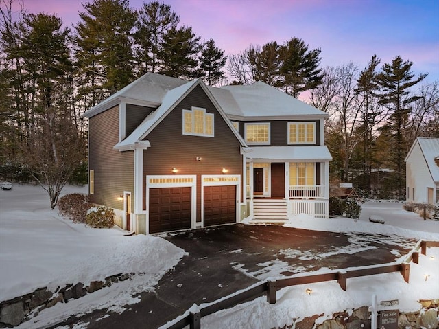 traditional-style house featuring a garage, covered porch, and aphalt driveway