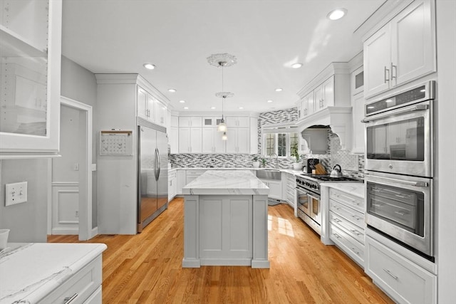 kitchen with white cabinets, pendant lighting, premium appliances, and a center island