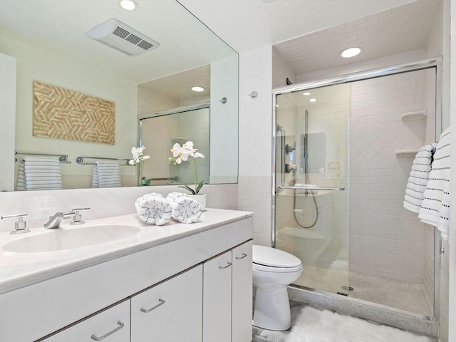 bathroom featuring a shower with door, vanity, and toilet