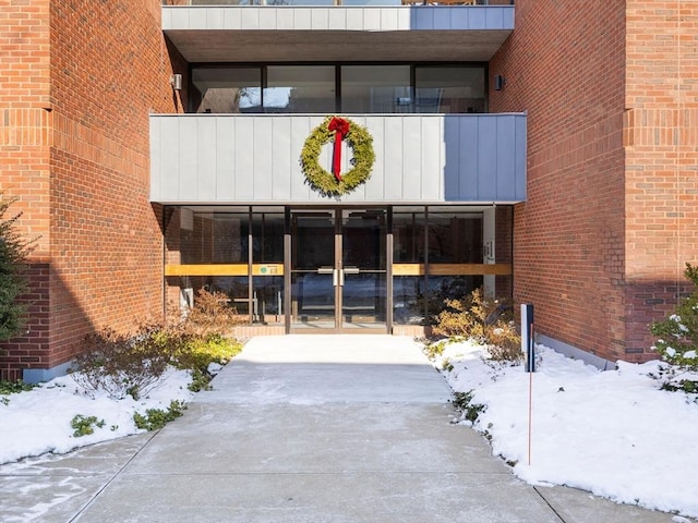 snow covered property entrance with a balcony