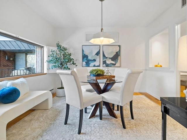 dining space with a baseboard heating unit and light hardwood / wood-style floors