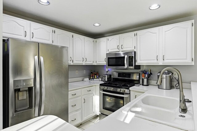 kitchen featuring appliances with stainless steel finishes, white cabinetry, light countertops, recessed lighting, and a sink