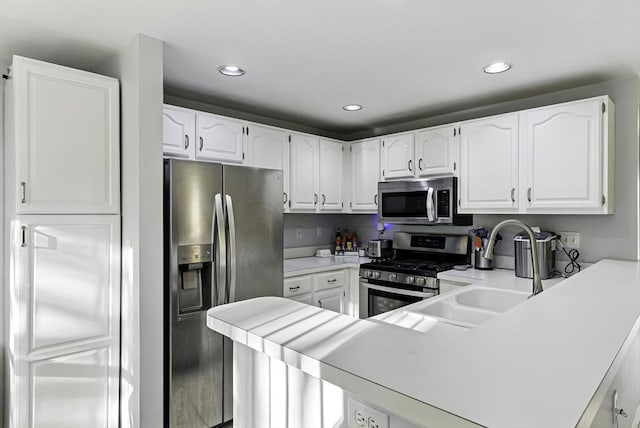 kitchen featuring stainless steel appliances, a peninsula, white cabinetry, a sink, and light countertops