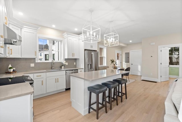 kitchen with hanging light fixtures, appliances with stainless steel finishes, and white cabinets