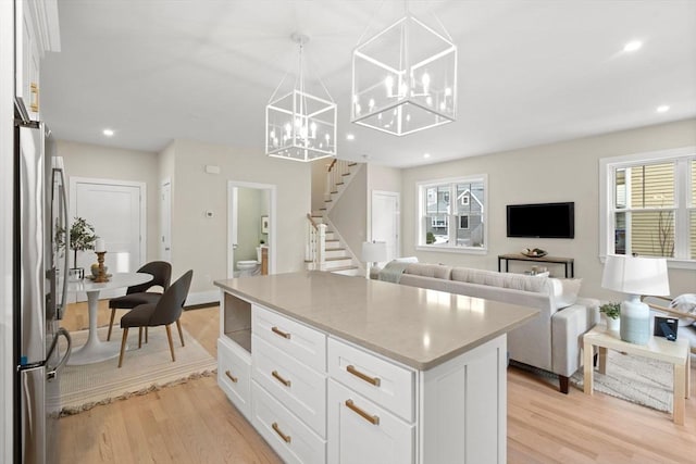 kitchen featuring light countertops, hanging light fixtures, open floor plan, white cabinetry, and a kitchen island