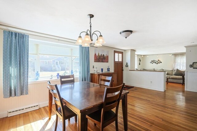 dining room featuring a baseboard heating unit, hardwood / wood-style floors, a chandelier, and plenty of natural light