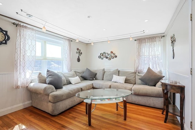 living room featuring a wainscoted wall, wood finished floors, and crown molding
